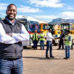 Transport operator standing in front of a fleet of trucks, buses and heavy equipment